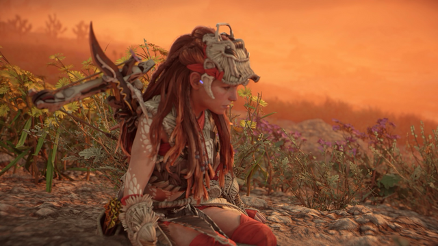 Shot from Horizon Forbidden West. Aloy on a mountain with orange haze behind.