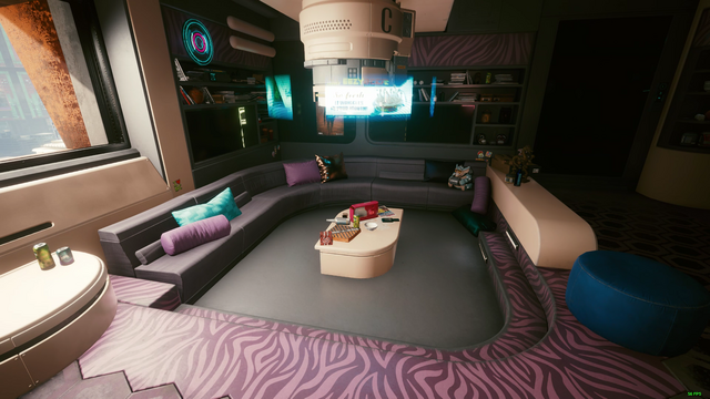 There's a living room area with sofas, all black, and purple accents. Pillows are scattered around for comfortable. There are black bookshelves, and a window beside the sofa with light pouring in. The carpeted floor is also black. There are two steps, which have a zebra print on them with shades of purple.