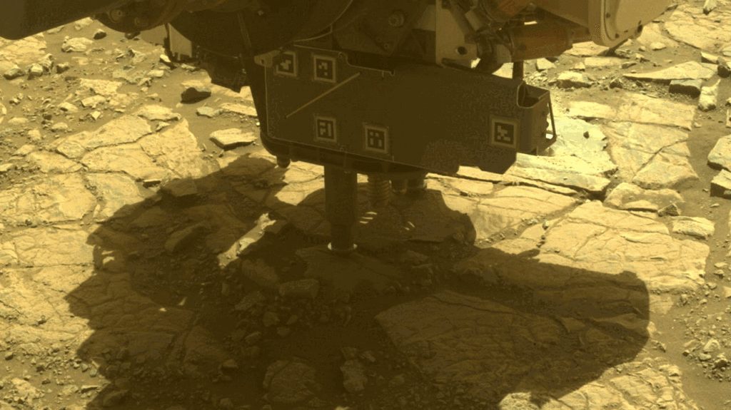 A drill going into a rocky yellowish ground.