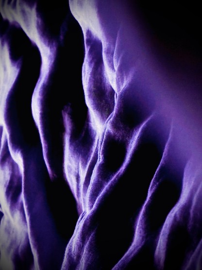 An extreme close-up view of a duvet gives a somewhat abstract, purple-hued cosmic impression.