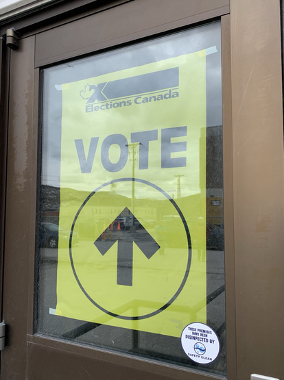 A yellow sign with an arrow, and the words vote in large print, and Elections Canada in smaller print.