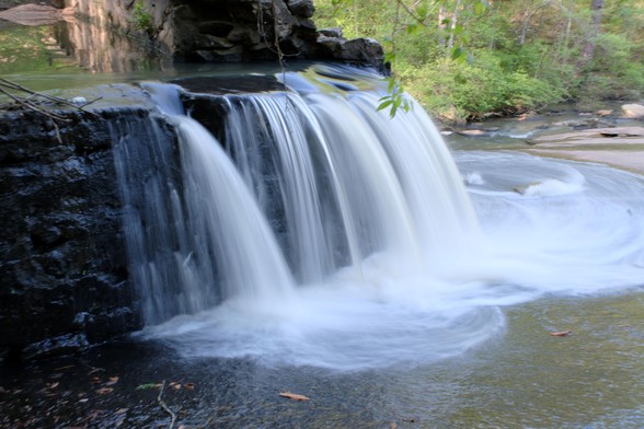 A slow-shutter speed shot of a waterfall. Silky water coming down from a rock brick wall onto a flat sheet of rock