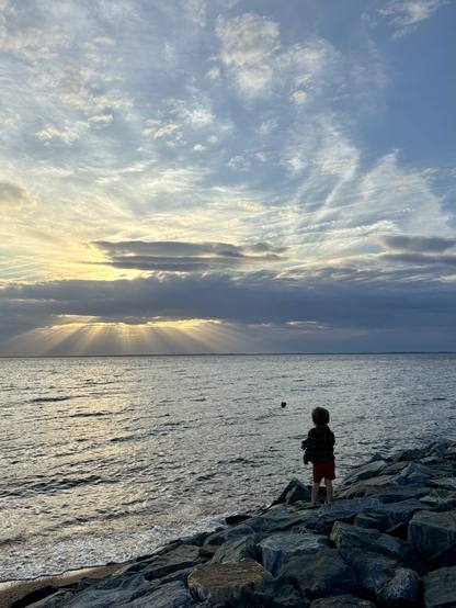 Sunset over the Chesapeake bay. A boy throwing a rock 