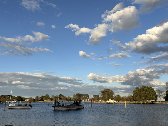 Evening on the creek. Puffy white clouds overhead. Two workboats docked for the evening. 